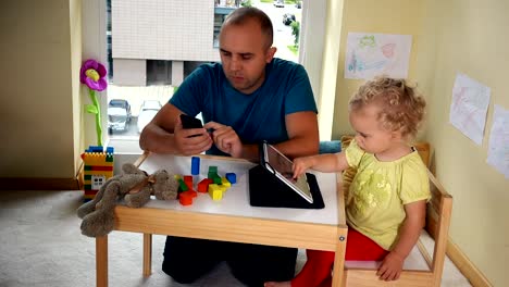 Vater-mit-Smartphone-und-Tochter-Mädchen-mit-Tablet-Computer