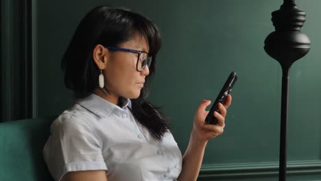 Long-haired-businesswoman-types-on-black-smartphone-closeup