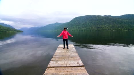 Das-Mädchen-im-roten-Mantel-steht-auf-dem-Pier-In-virtual-Reality-Brille