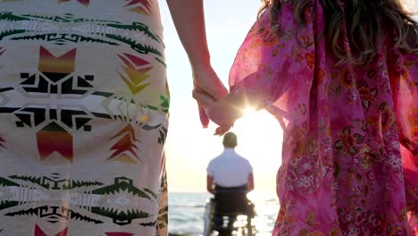 mother-and-daughter-keep-hands-on-background-father-sitting-in-wheelchair