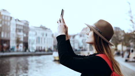 Excited-Caucasian-tourist-lady-enjoying-old-town.-Female-with-long-hair-in-fashionable-hat-films-amazing-city-view.-4K