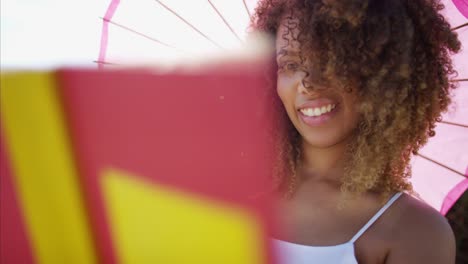 Ethnic-female-reading-book-on-beach-at-sunset