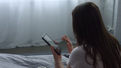 Adult-woman-using-tablet-pc-sitting-on-the-bed