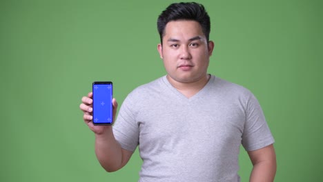 Young-handsome-overweight-Asian-man-against-green-background