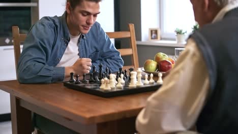 Senior-Man-in-Wheelchair-Playing-Chess-with-Grandson