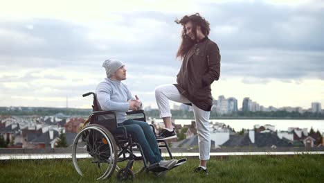 Happy-disabled-man-in-a-wheelchair-with-woman-talking-on-the-hill