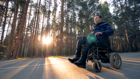 Physically-challenged-man-is-moving-in-a-powered-wheelchair-along-the-road