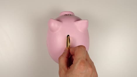 TOP-VIEW:-Human-hand-throws-a-coin-into-pink-pig-money-box