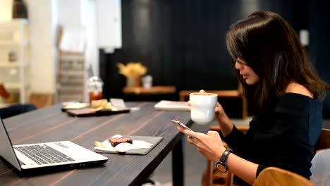 Mujer-asiática-disfrutando-de-su-café-y-smartphone-en-café