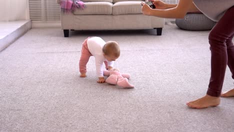 Mother-photographing-playful-baby-girl-using-mobile-phone-camera