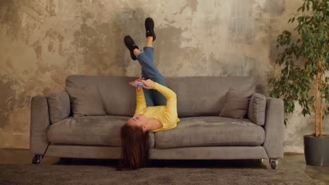 Joyful-woman-with-cellphone-relaxing-on-sofa