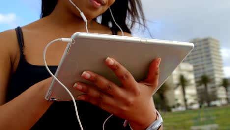 Nahaufnahme-der-behinderte-Frau-Musik-hören-auf-digitale-Tablet-im-Park-4k