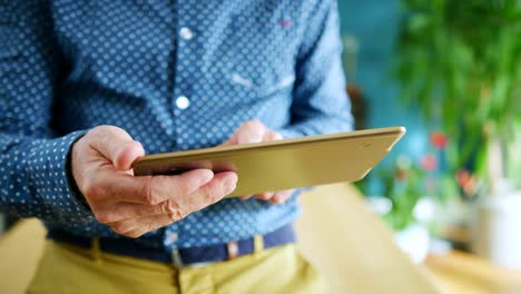 Businessman-Swiping-Through-Digital-Tablet-At-Home-Office