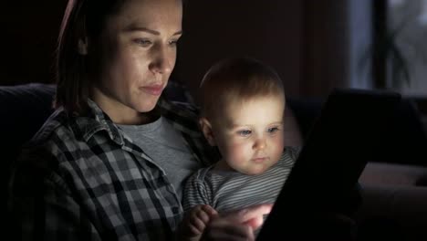 Mother-with-baby-girl-using-digital-tablet-at-night