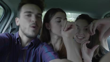 Happy-teenage-man-taking-selfie-video-streaming-with-couple-dancing-funny-crazy-girls-while-they-going-on-summer-holiday-party-and-fun-roadtrip-concept