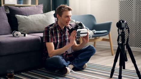 young-man-blogger-is-recording-video-about-virtual-reality-glasses-sitting-on-floor-at-home