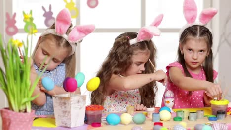 Happy-children-wearing-bunny-ears-painting-eggs-on-Easter-day.