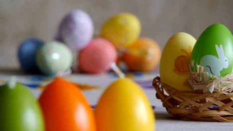 Close-up.-Candles-made-in-shape-of-easter-egg.-Easter-eggs-candles-and-colorful-Easter-eggs-in-the-background.-Refocusing.