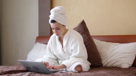 Woman-with-Towel-on-Head-Using-Laptop-on-Bed