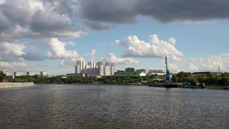 Vista-aérea-del-puente-ferroviario,-con-un-tren-en-movimiento-en-él,-a-través-del-río-que-fluye-a-través-de-una-ciudad-importante