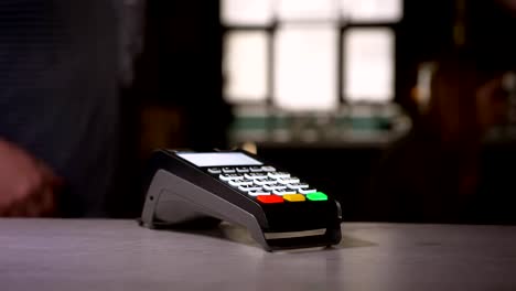 Close-up-shot-of-woman-attaches-smartphone-to-terminal-performing-successful-contactless-payment-getting-a-cup-of-coffee.