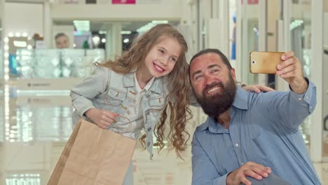 Entzückende-kleine-Mädchen-machen-Selfies-mit-ihrem-Vater-in-der-Shopping-Mall