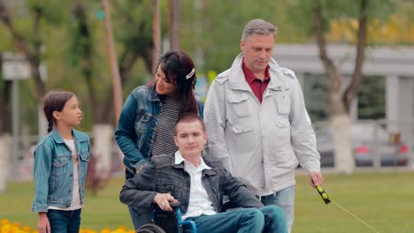 Young-man-with-disabilities-is-in-the-city-with-his-family.-Caring-mom-is-carrying-her-son-in-a-wheelchair.