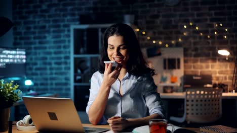 Young-lady-using-smartphone-touching-screen-talking-working-overtime-at-night