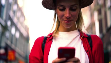 Efecto-de-cámara-lenta-de-la-mujer-caucásica-en-la-notificación-de-comprobación-de-sombrero-de-moda-en-el-teléfono-móvil-de-pie-en-la-calle