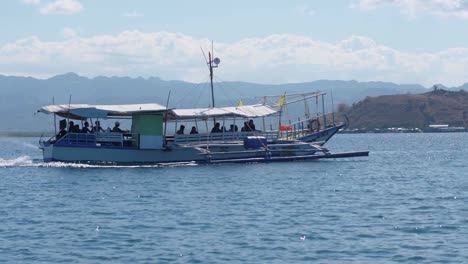 Pequeño-barco-con-turistas-viajan-en-el-océano-azul-yendo-a-una-hermosa-isla.