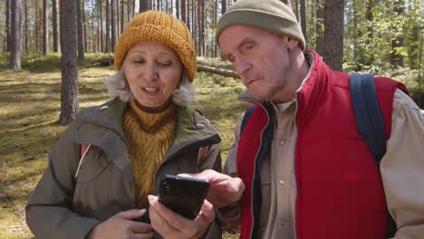 Par-de-excursionistas-envejecidos-que-usan-el-teléfono-durante-el-paseo