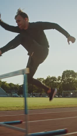 Athletic-Fit-Hombre-en-camisa-gris-y-pantalones-cortos-Hurdling-en-el-estadio.-Está-saltando-sobre-las-barreras-en-una-cálida-tarde-de-verano.-Disparo-de-seguimiento-de-cámara-lenta.-Video-de-orientación-vertical-de-la-pantalla-9:16