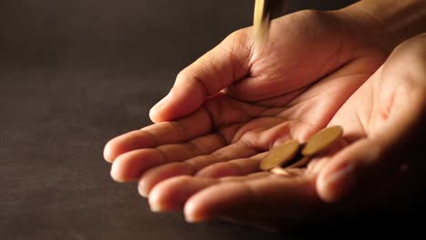 Hand-holding-a-big-heap-of-coins-and-throwing-them-on-table