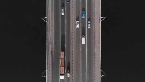 Timber-truck-on-bridge-highway-in-traffic-aerial-top-view