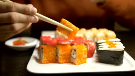 Ein-junger-Mann-isst-Brötchen-in-einem-asiatischen-Restaurant-und-fotografiert-sie-auf-einem-Smartphone