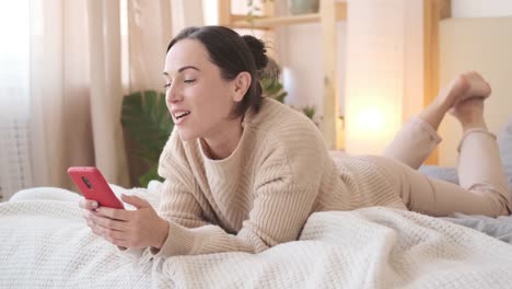 Woman-using-mobile-phone-and-singing-song-while-relaxing-on-bed