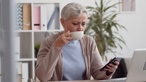 Frau-mittleren-Alters,-die-Kaffeepause-am-Arbeitsplatz-hat