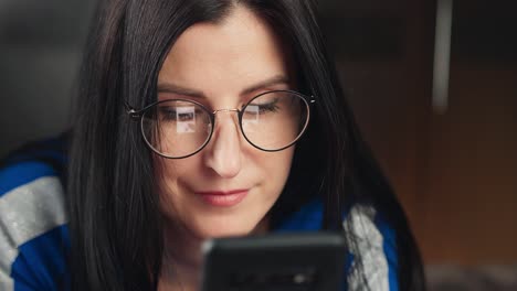 Nahaufnahme-angenehme-Mädchen-in-Brille-Blick-auf-Bildschirm-des-Smartphones.-4k-Dragon-RED-Kamera