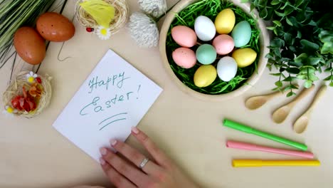 Hand-with-marker-doing-postcard-and-Easter-decorations-on-wooden-background