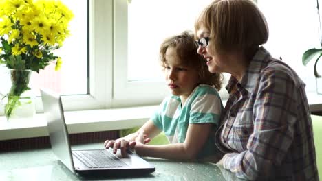 Der-Junge-jüngeren-Schulalter-hilft-der-älteren-Frau,-den-Computer-zu-beherrschen.