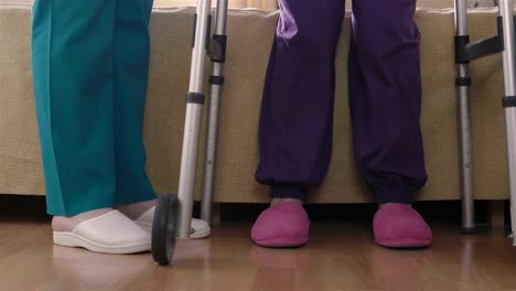 Care-assistant-teaching-elder-disabled-woman-how-to-walk-with-walker