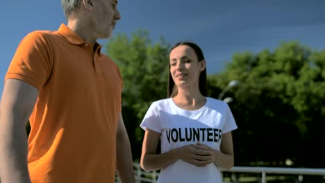 Mujer-amable-alegre-voluntaria-caminando-con-un-hombre-mayor