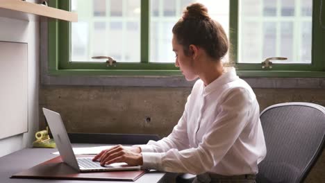 Woman-reading-document-and-using-laptop-in-office,-close-up