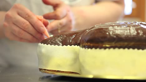 pastry-chef-hands-garnish-Easter-sweet-bread-cakes-with-piping-bag,-closeup-on-the-worktop-in-confectionery