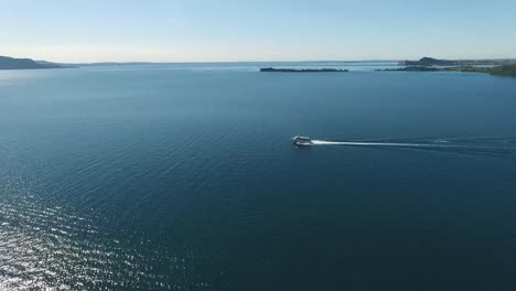 flying-over-the-surface-of-the-Lake-Garda-water-surrounded-by-mountains,-Italy.-video-shooting-with-drone