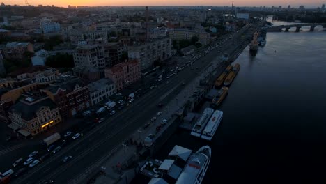 Traffic-jam-on-the-road-along-the-river-with-boats-at-sunset-aerial