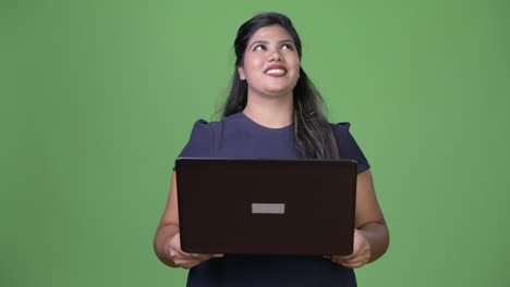 Young-overweight-beautiful-Indian-businesswoman-against-green-background