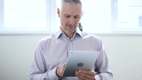 Medio-de-años-hombre-navegar-por-Internet-en-Tablet-en-oficina