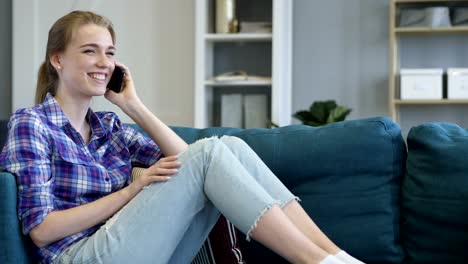 Junge-Frau-telefonieren-beim-Entspannen-auf-der-Couch