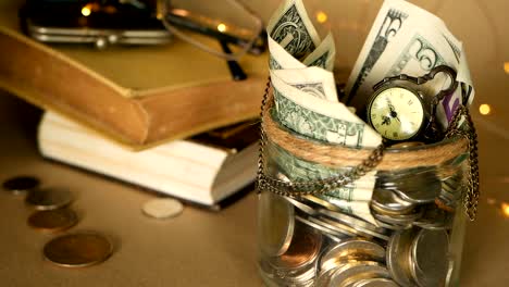 Books-with-glass-penny-jar-filled-with-coins-and-banknotes.-Tuition-or-education-financing-concept.-Scholarship-money.